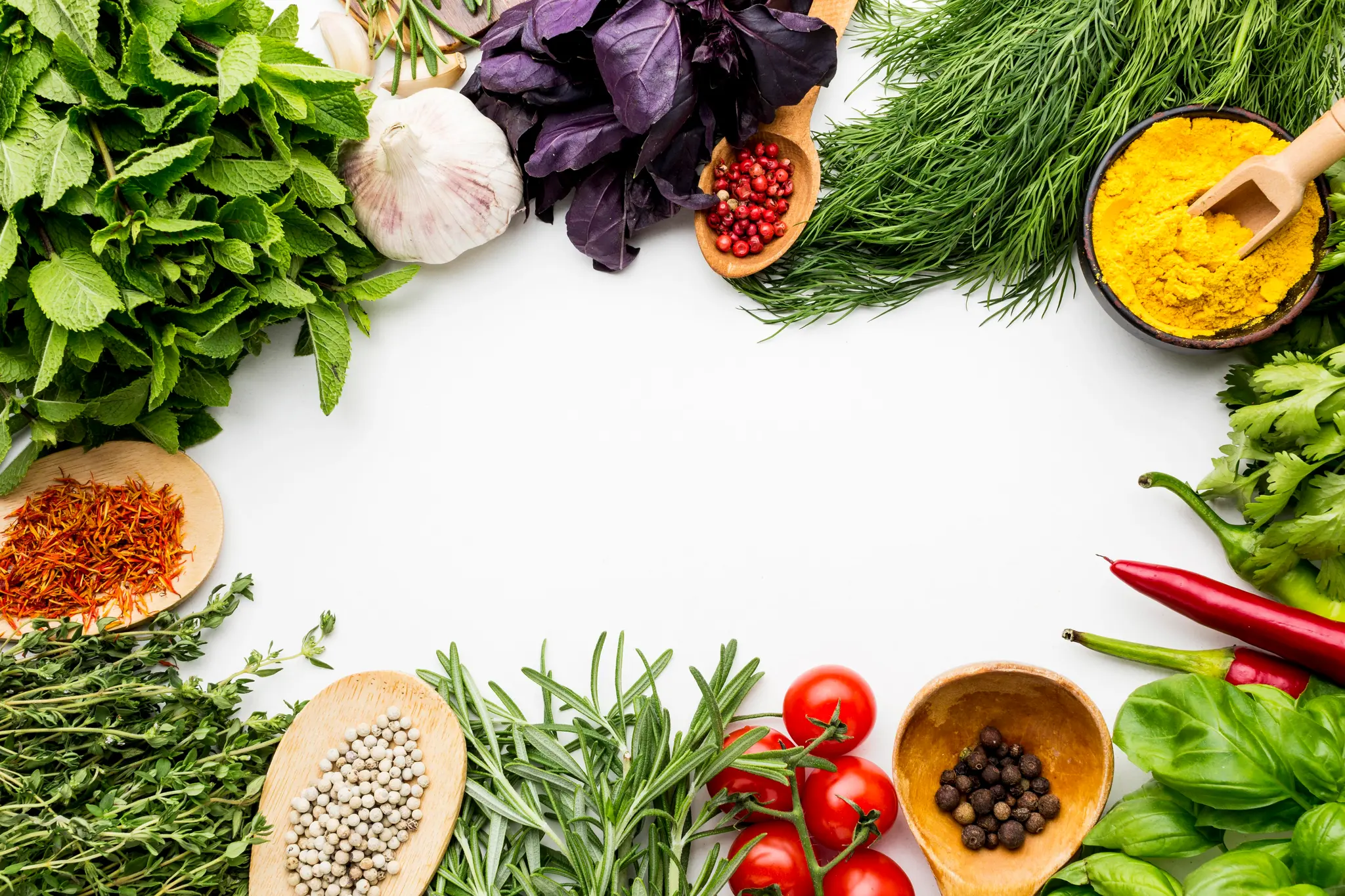 Fresh herbs, spices, chillies and tomatoes arranged around a white surface